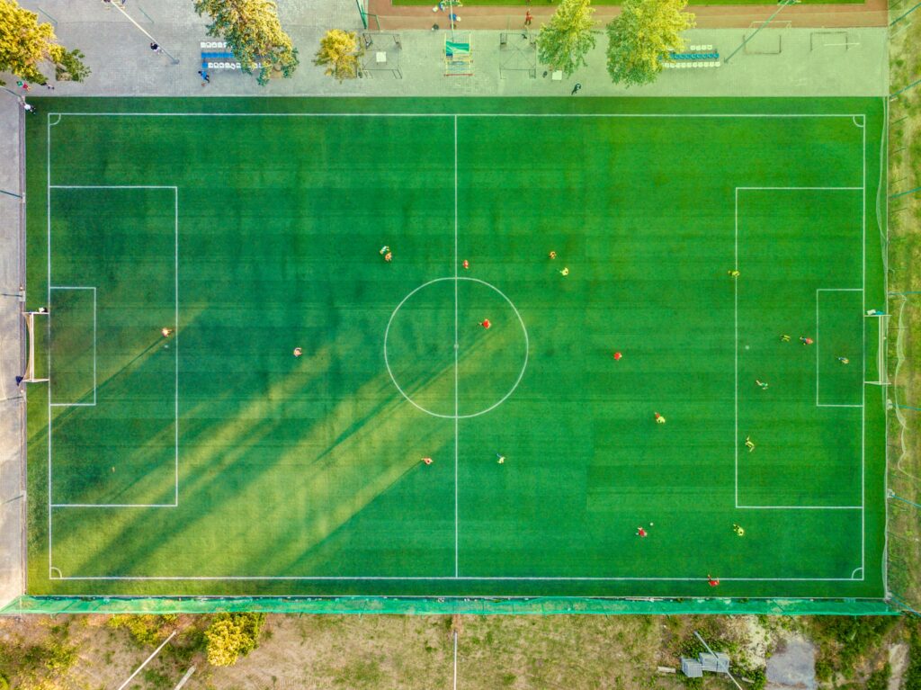 Aerial shot of a soccer game with players on a vibrant green field.