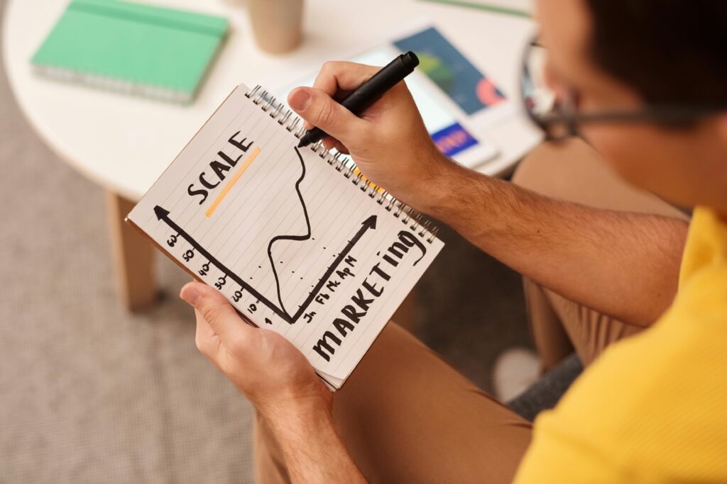 Close-up of a man drawing a marketing strategy graph in a notebook.