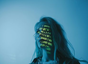 A woman with binary code lights projected on her face, symbolizing technology.