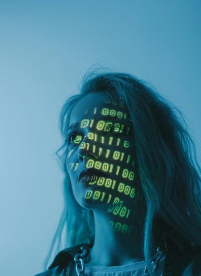 A woman with binary code lights projected on her face, symbolizing technology.